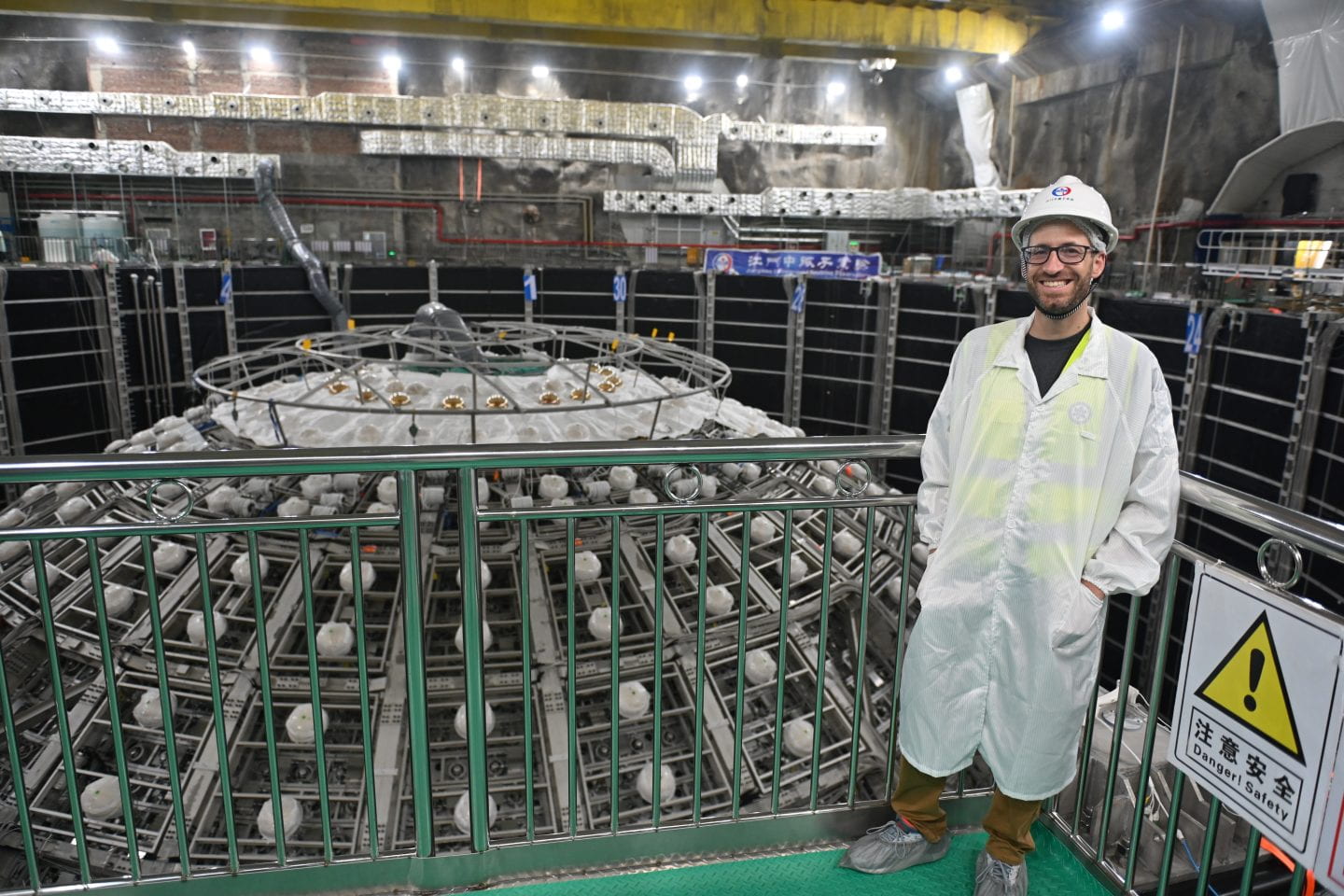 Physicist Pedro Ochoa-Ricoux stands next to JUNO particle detector under construction.